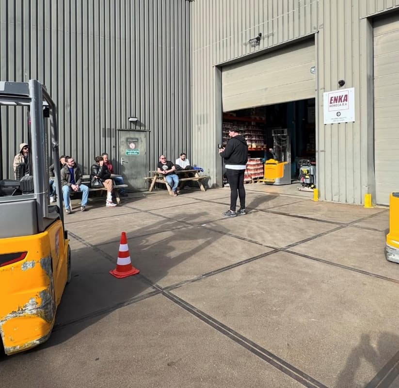 Instructeur geeft uitleg aan een groep deelnemers op het bedrijfsterrein